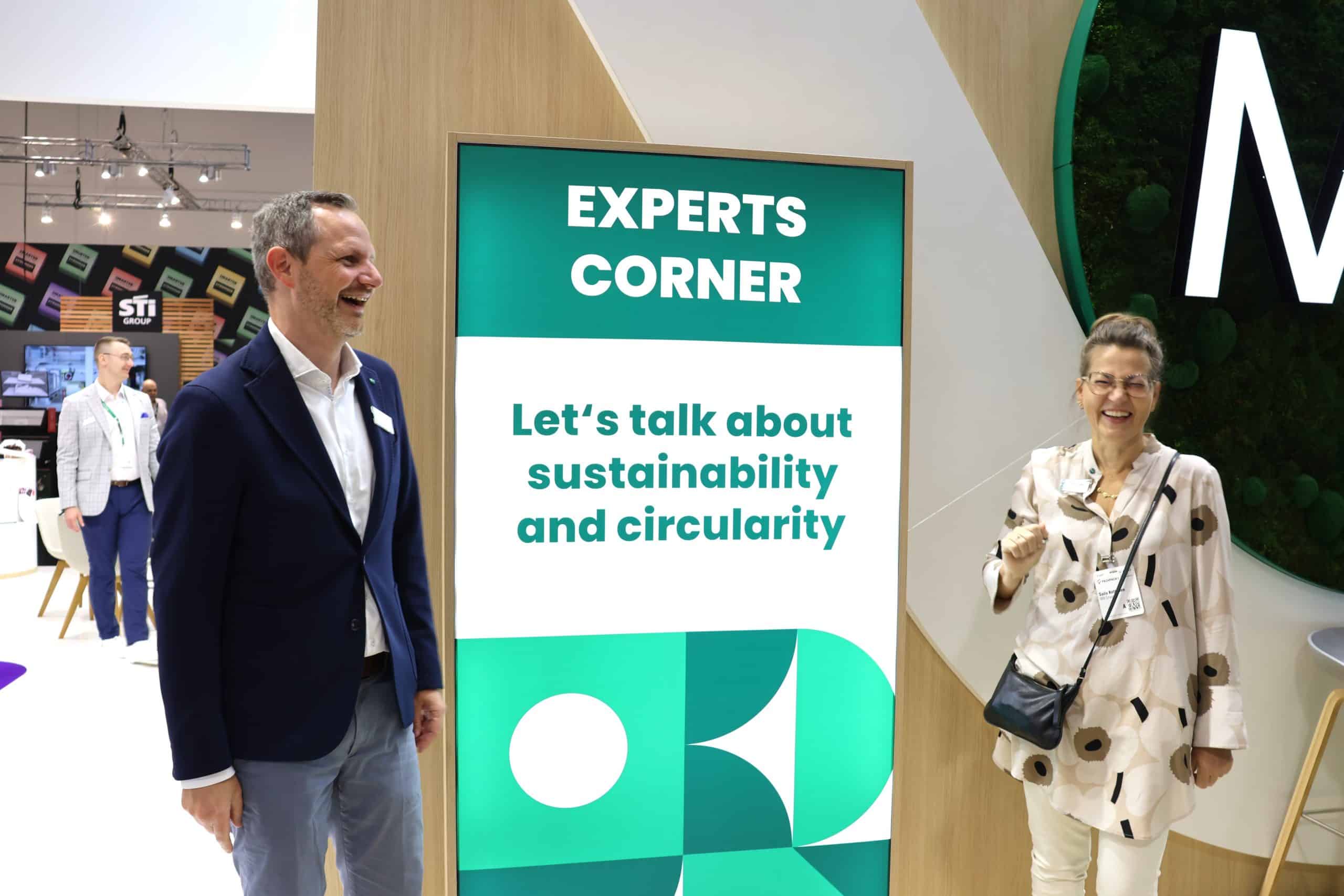 Packaging industry experts at FACHPACK 2025, standing next to a MM display reading “EXPERTS CORNER: Let’s talk about sustainability and circularity.” 