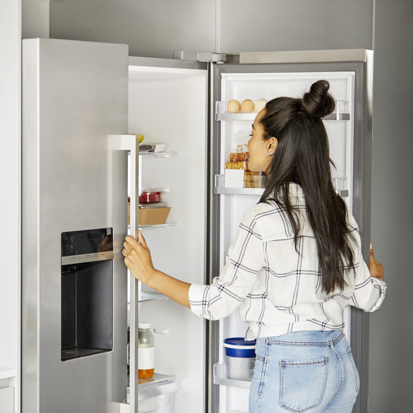 Woman looking for food in refrigerator at home